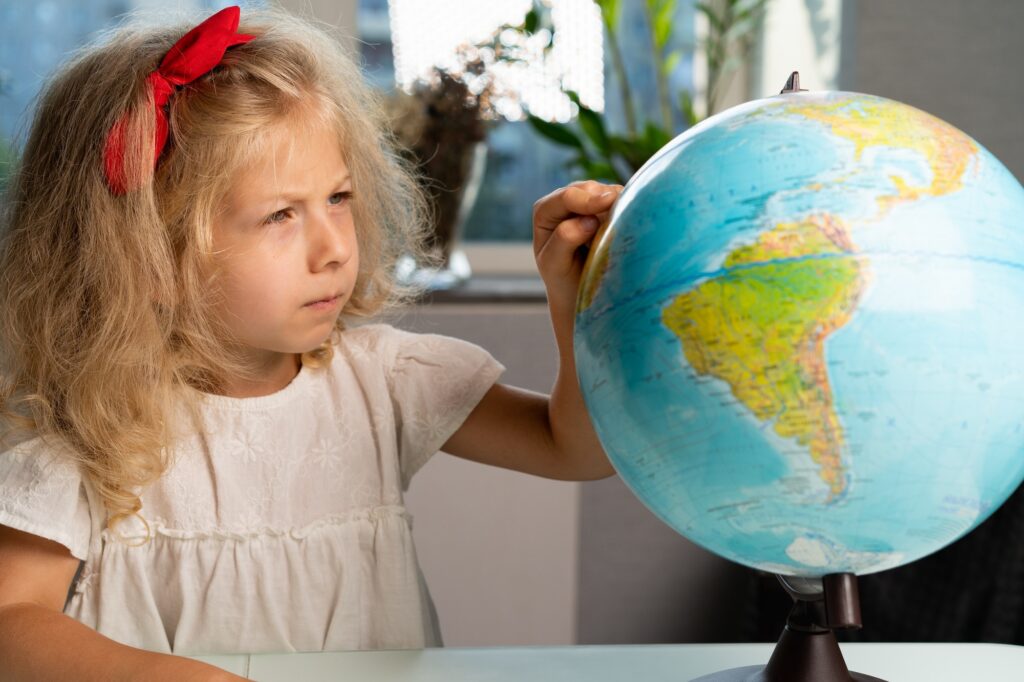 Little girl smiles with a globe, studying geography, traveling, freedom, dreams, cute children