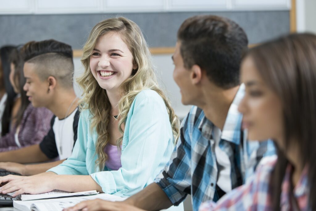 Row of teenage high school students smiling in computer class